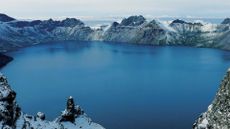 A view of a blue alpine lake surrounded by snowy mountains