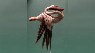 A swan made out of pink and brown felt against a green background